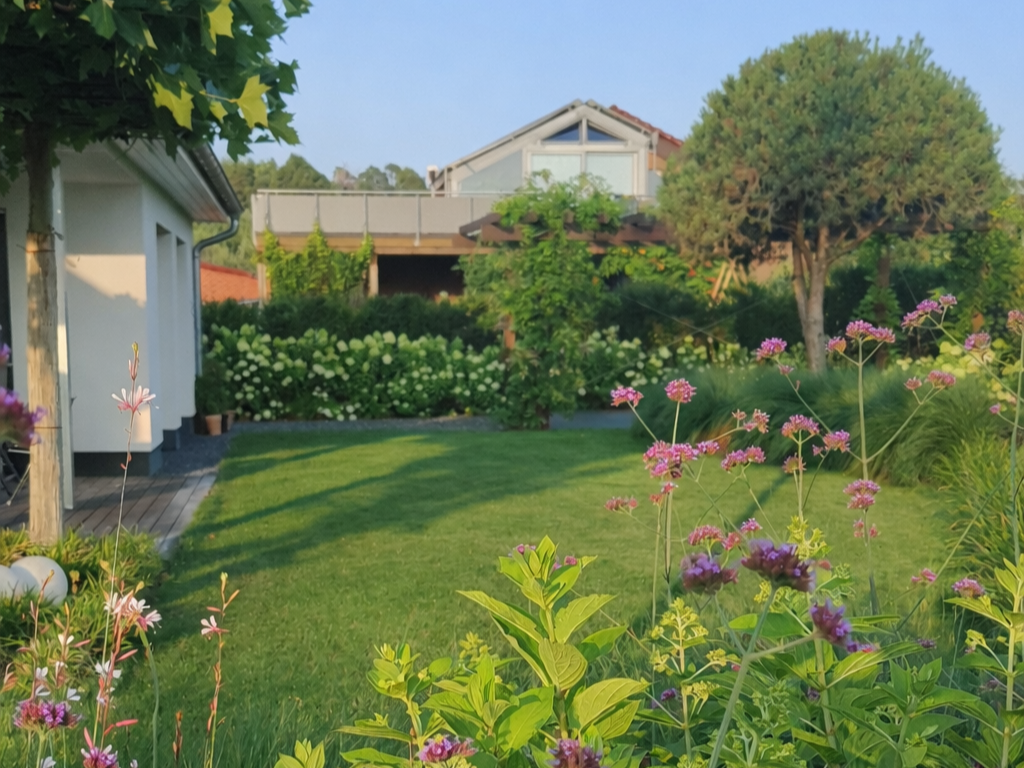 Blühende Gartenanlage mit großen Bäumen und einer Pergola