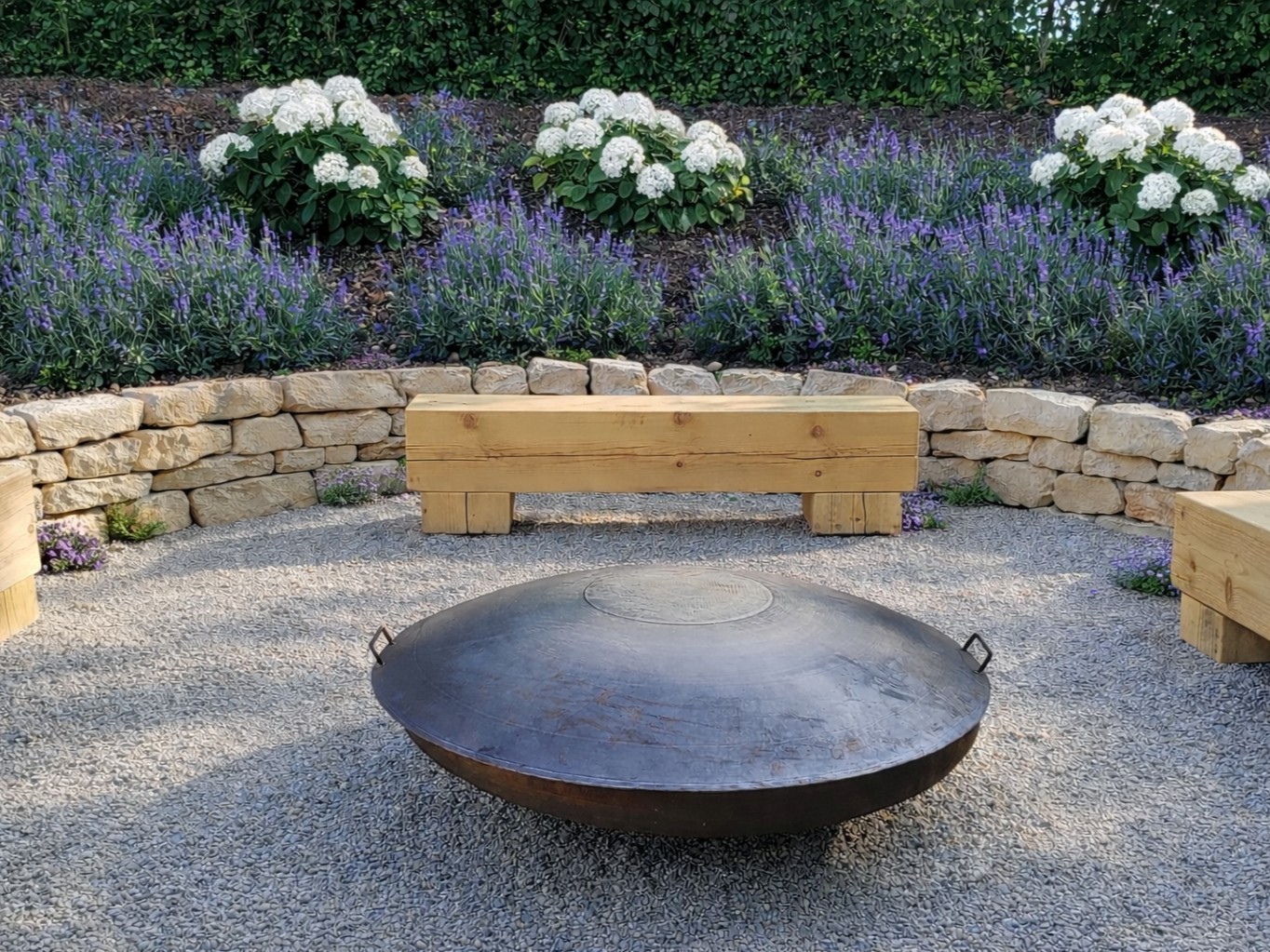 Grillstelle mit Trockenmauern und Holzbänken und Lavendel